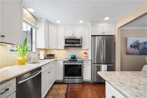 a kitchen with a refrigerator a microwave a sink and wooden floor