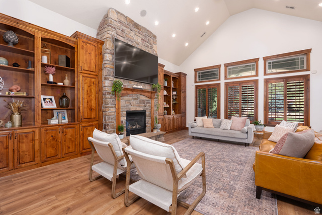 687 South 2080th Street East Springville, UT 84663 - Photo 12 of 149 Vaulted ceiling living space with a stone fireplace, built-in wooden cabinetry, wood-finish flooring, and plantation shutters