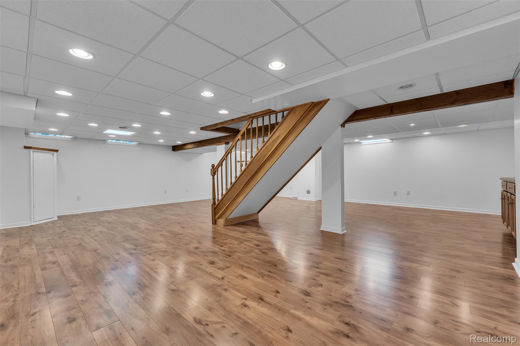 7000 Woonsocket Street Canton, MI 48187 - Photo 53 of 65 Spacious room featuring wood-finish flooring, a wood staircase with balusters, and exposed wood beams