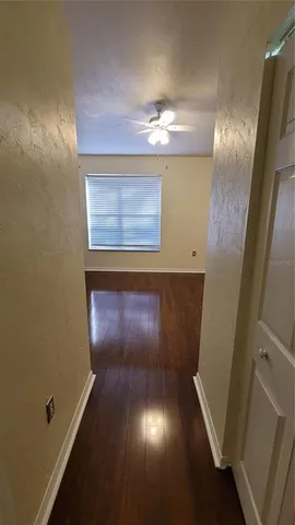 an empty room with wooden floor fan and windows