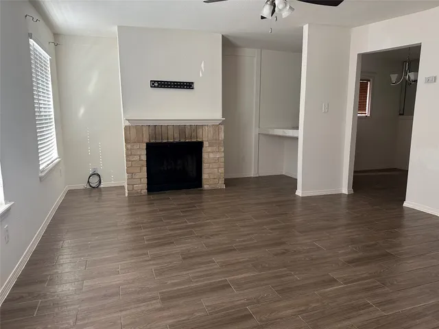 a view of an empty room with wooden floor and a fireplace