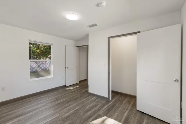 an empty room with wooden floor and window