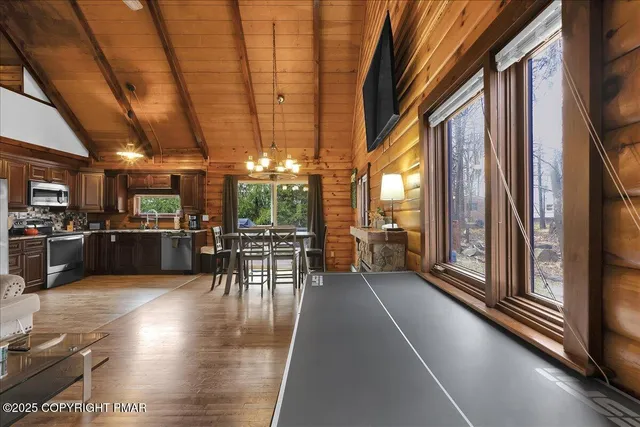a living room with stainless steel appliances dining table furniture and a large window