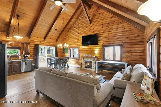 a living room with couches chairs and flat screen tv with kitchen view