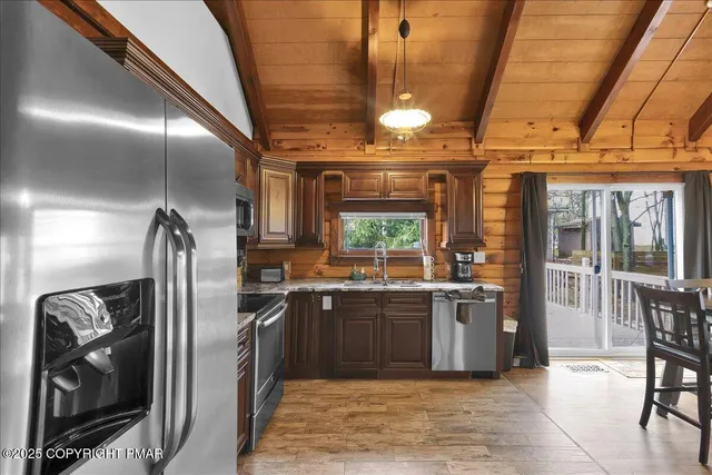 a kitchen with stainless steel appliances granite countertop a sink a stove a refrigerator cabinets and a dining table with wooden floor