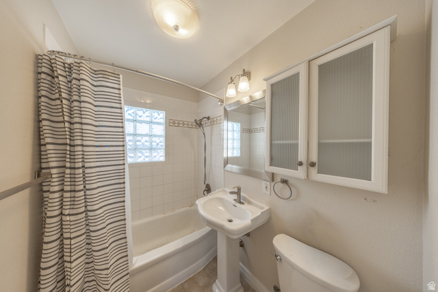 193 Locust Street Clearfield, UT 84015 - Photo 12 of 29 Bathroom featuring a pedestal sink, white tile shower surround with glass block window, and dual wall-mounted storage cabinets with reeded glass inserts