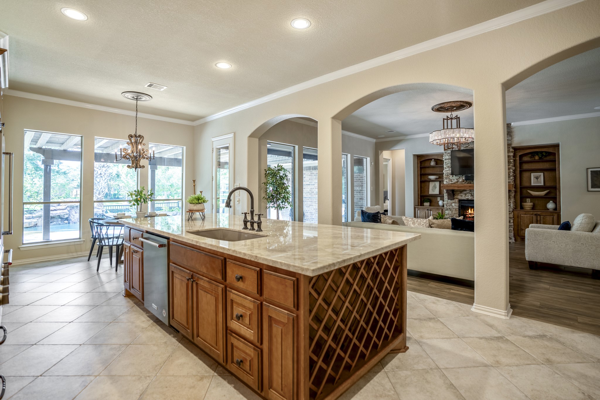 2407 Hendricks Lakes Drive Spring, TX 77388 - Photo 14 of 50 The island draws the space together with Taj Mahal quartzite, rich Benedettini cabinetry, and undercabinet lighting giving the room its custom, elevated feel. The breakfast nook sits ahead near the windows, pulling natural light toward the back of the home, while the arched openings on the right keep the kitchen connected to the living room and the poolside, water-front setting beyond.
