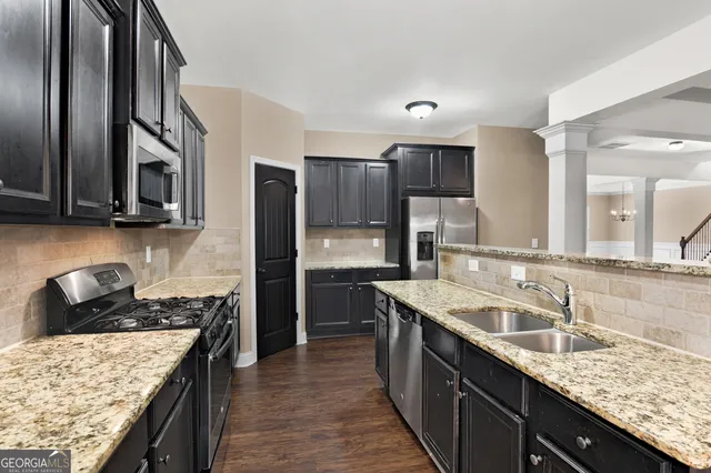 a kitchen with stainless steel appliances granite countertop a sink stove microwave and refrigerator