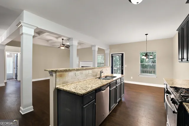 a dining hall with stainless steel appliances granite countertop a kitchen island a stove and a sink