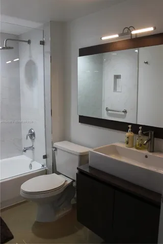 a bathroom with a sink a toilet a mirror and bathtub
