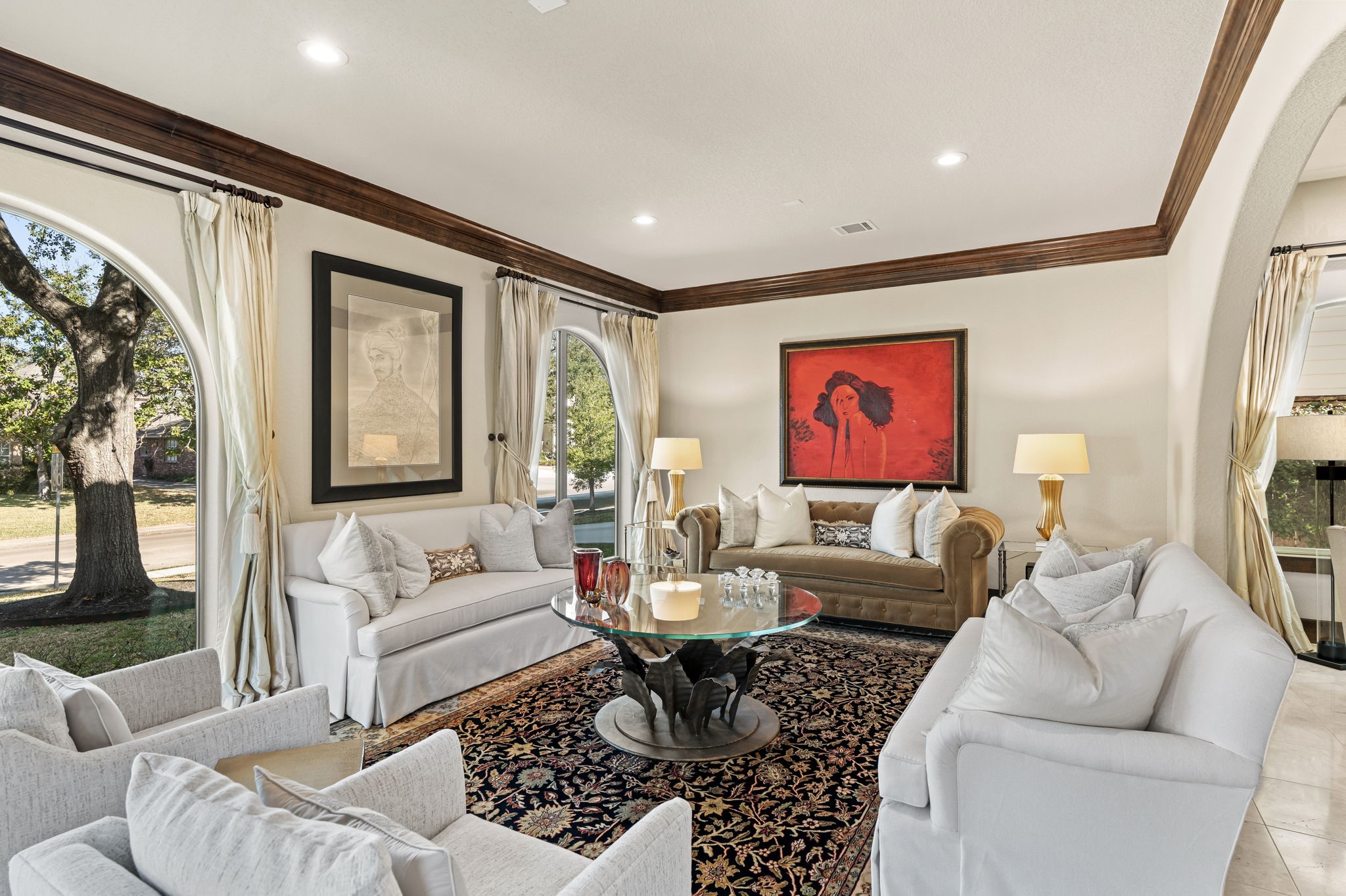 3751 Aberdeen Way Houston, TX 77025 - Photo 4 of 39 A light-filled formal living room with arched windows, high ceilings, and rich wood crown molding, offering a balanced, symmetrical layout and an elegant connection to the outdoors through multiple large openings.
