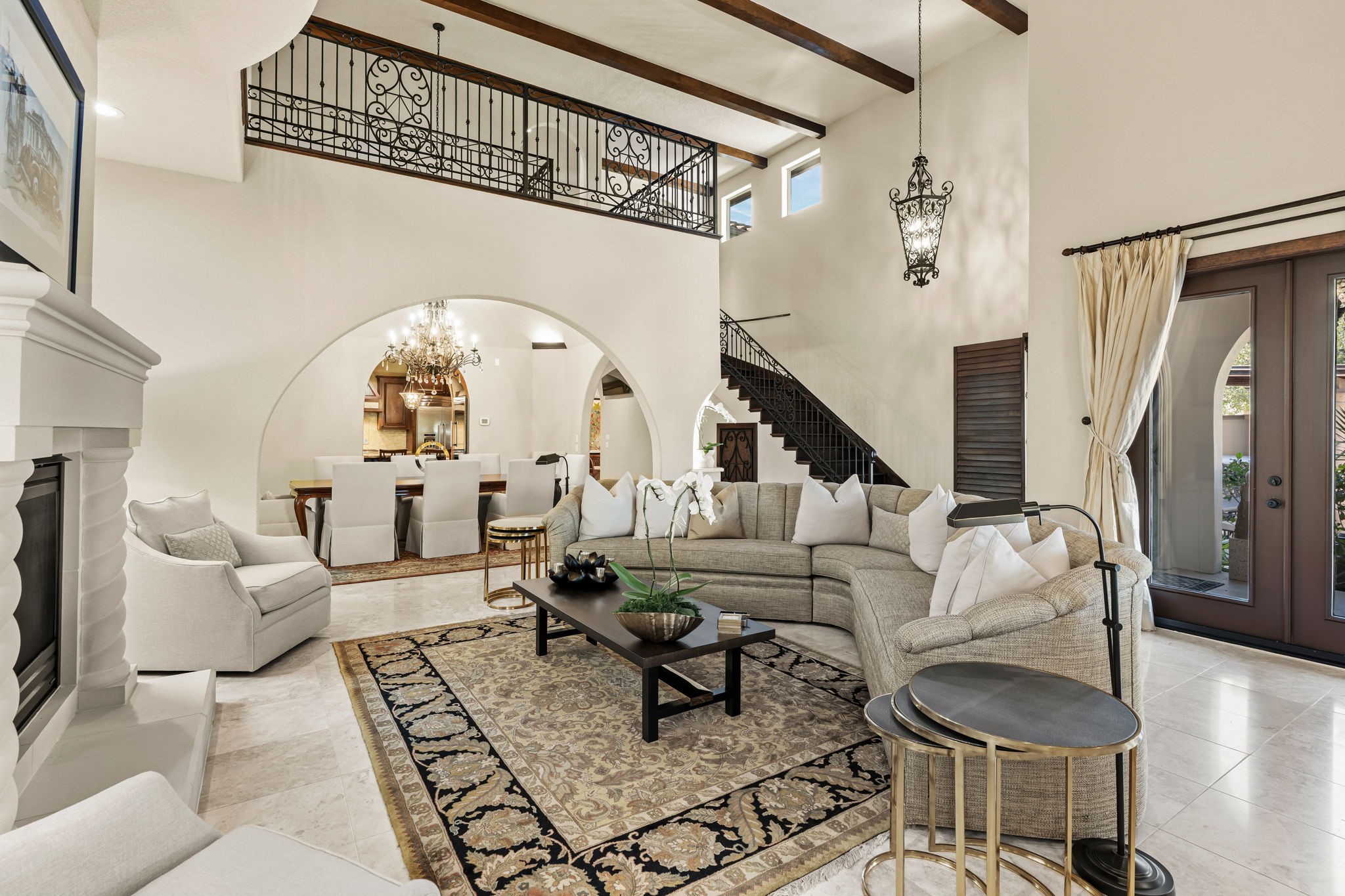 3751 Aberdeen Way Houston, TX 77025 - Photo 8 of 39 A spacious, open family room with soaring ceilings, exposed wood beams, and arched openings, anchored by a dramatic two-story layout that connects seamlessly to the dining area and upper-level walkway.