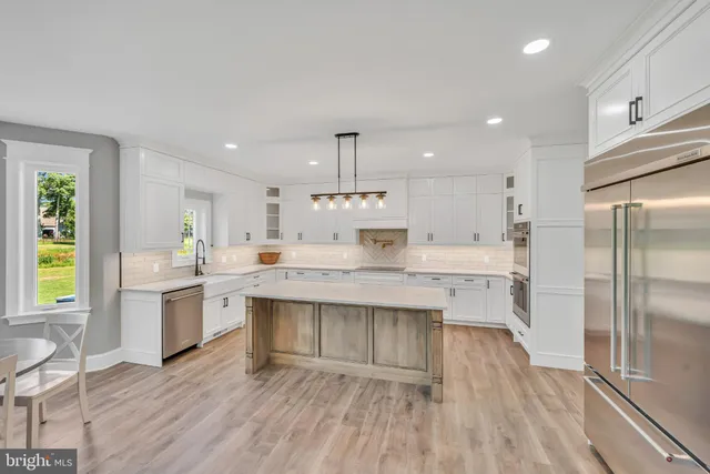a kitchen with kitchen island granite countertop a sink cabinets and stainless steel appliances