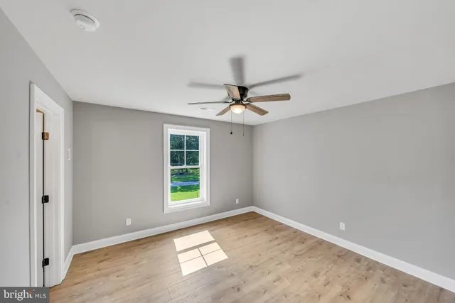 an empty room with a window and ceiling fan