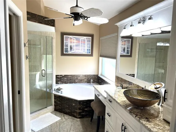 a bathroom with a granite countertop sink a mirror a bathtub and shower