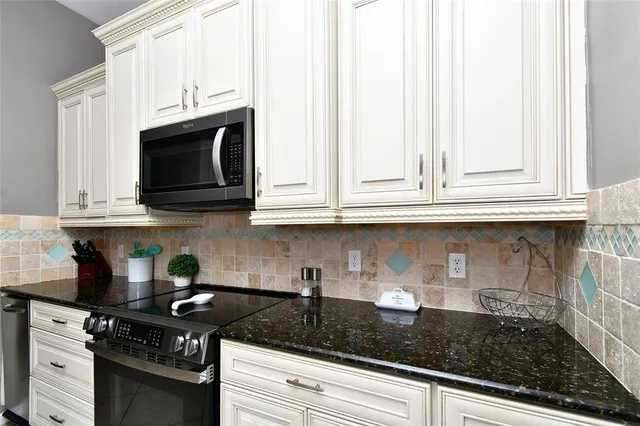 a kitchen with stainless steel appliances granite countertop white cabinets and a stove