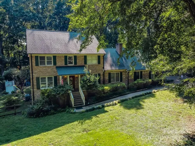 a aerial view of a house next to a yard with potted plants and large trees