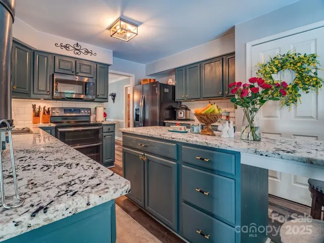 a kitchen with stainless steel appliances kitchen island granite countertop a stove refrigerator and a sink
