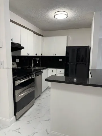 a kitchen with a refrigerator and a stove top oven