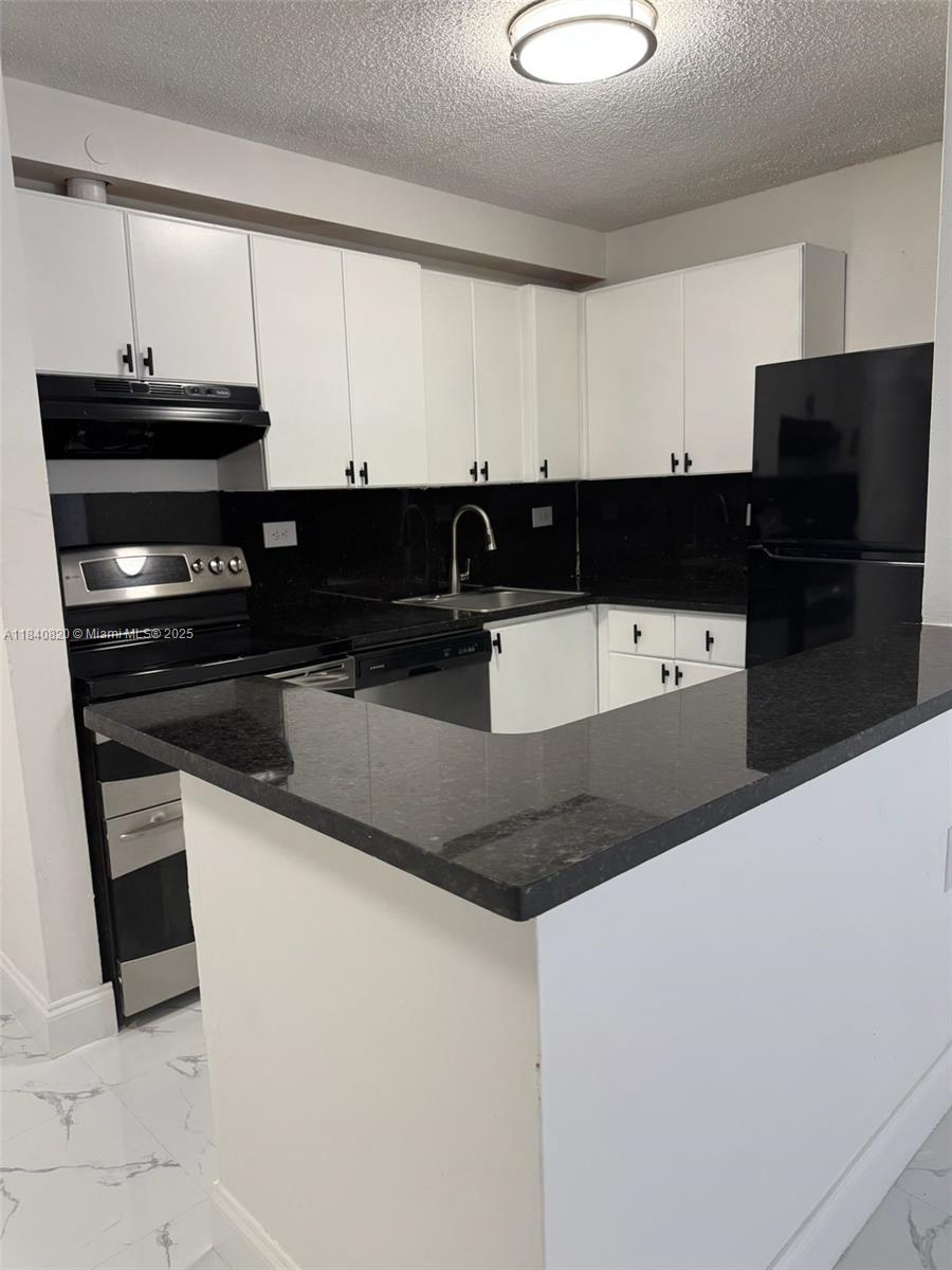 7010 Northwest 179th Street, Unit 105 Hialeah, FL 33015 - Photo 2 of 9 a kitchen with stainless steel appliances a refrigerator a stove and white cabinets