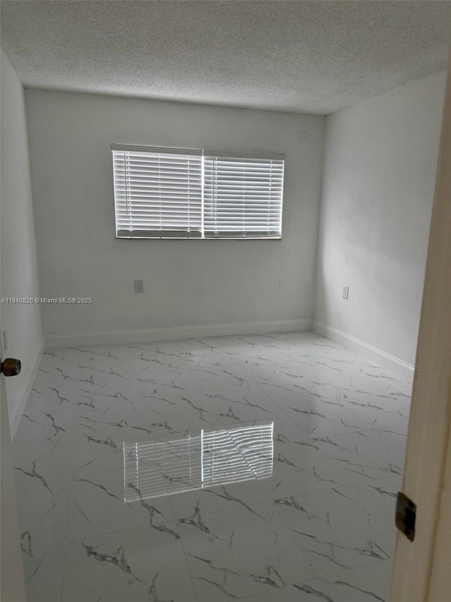 7010 Northwest 179th Street, Unit 105 Hialeah, FL 33015 - Photo 4 of 9 a view of an empty room with a window