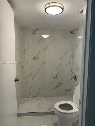 a bathroom with a granite countertop toilet and a shower