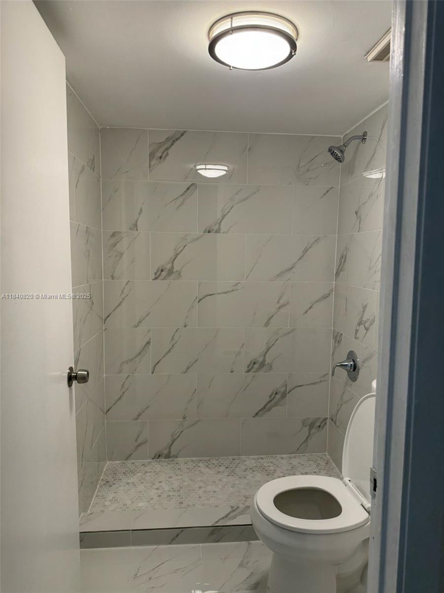 7010 Northwest 179th Street, Unit 105 Hialeah, FL 33015 - Photo 5 of 9 a bathroom with a granite countertop toilet and a shower