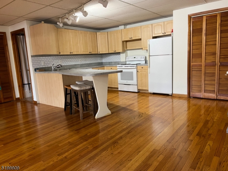 a kitchen with wooden floors and white stainless steel appliances