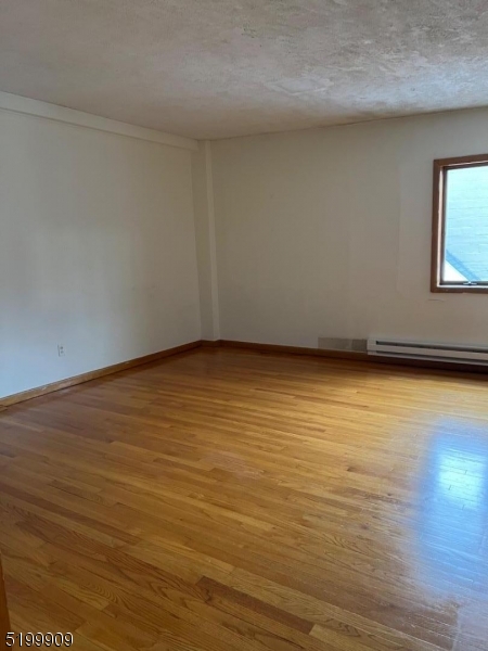 351 Springfield Avenue, Unit 3 Summit, NJ 07901 - Photo 5 of 6 a view of an empty room with wooden floor and a window