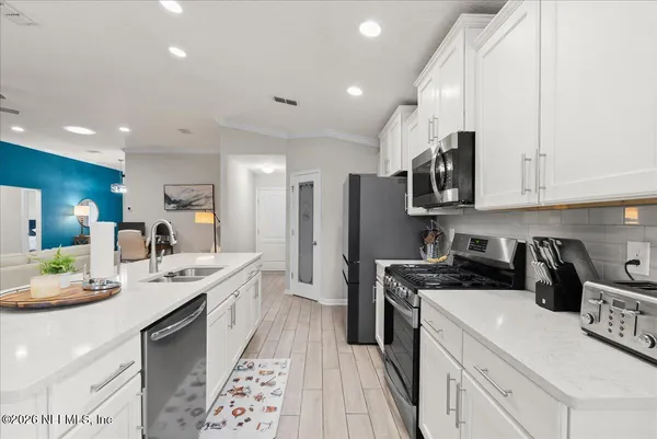 a kitchen with stainless steel appliances granite countertop a sink stove refrigerator and cabinets
