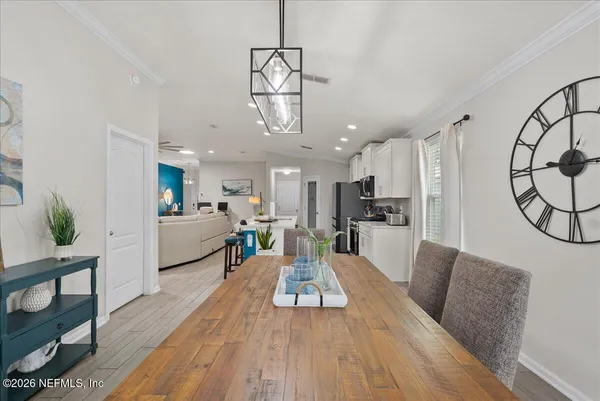 a view of a dining room and livingroom with furniture wooden floor a chandelier