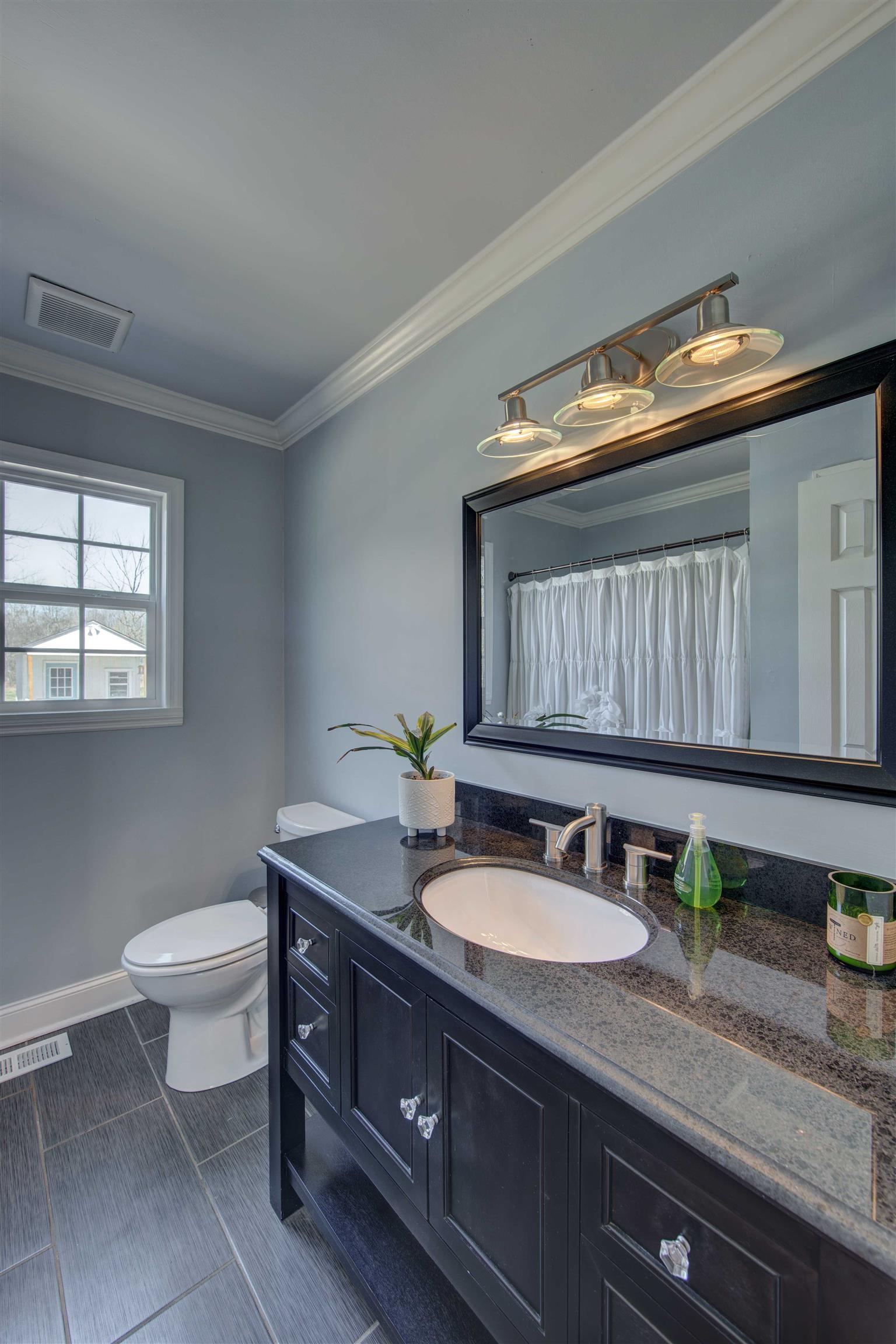 700 Baker Road Columbia, TN 38401 - Photo 16 of 30 a bathroom with a granite countertop sink a toilet and a mirror