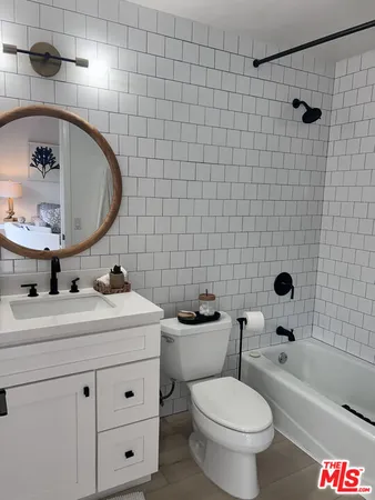 a bathroom with a toilet a sink a mirror and bathtub