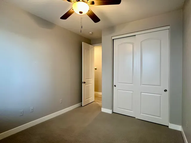 an empty room with ceiling fan and window