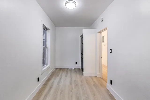 a view of empty room with wooden floor