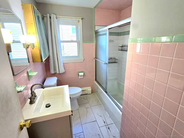 a bathroom with a sink a toilet a mirror and shower