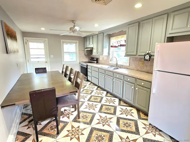 a kitchen with stainless steel appliances granite countertop sink refrigerator dining table and chairs