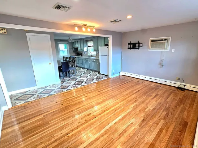 a view of a livingroom with wooden floor and kitchen view