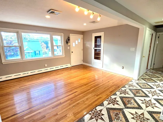 an empty room with wooden floor and windows