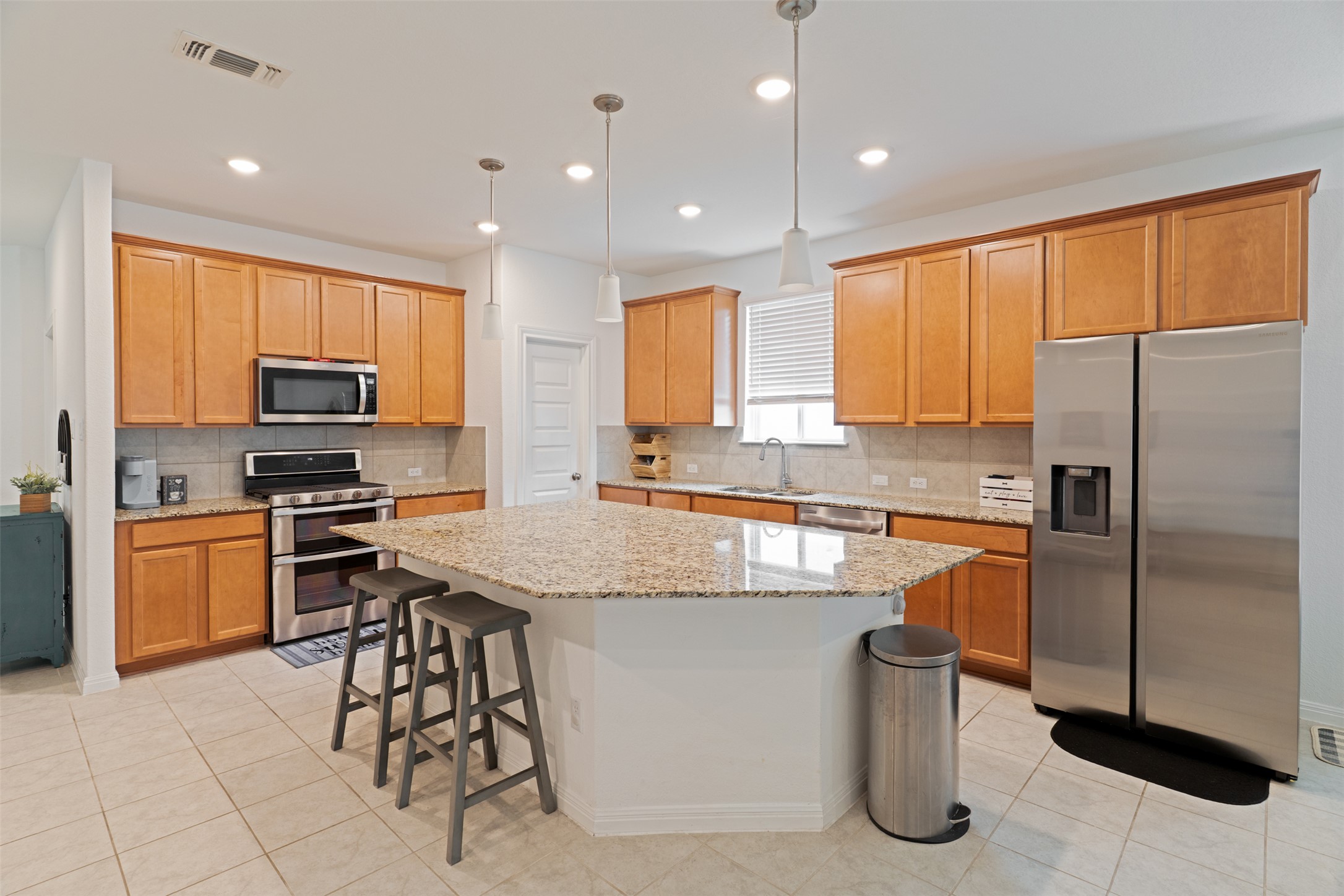 237 Rain Lily Lane Georgetown, TX 78626 - Photo 11 of 20 a kitchen with stainless steel appliances granite countertop a refrigerator a stove a sink a dining table and chairs