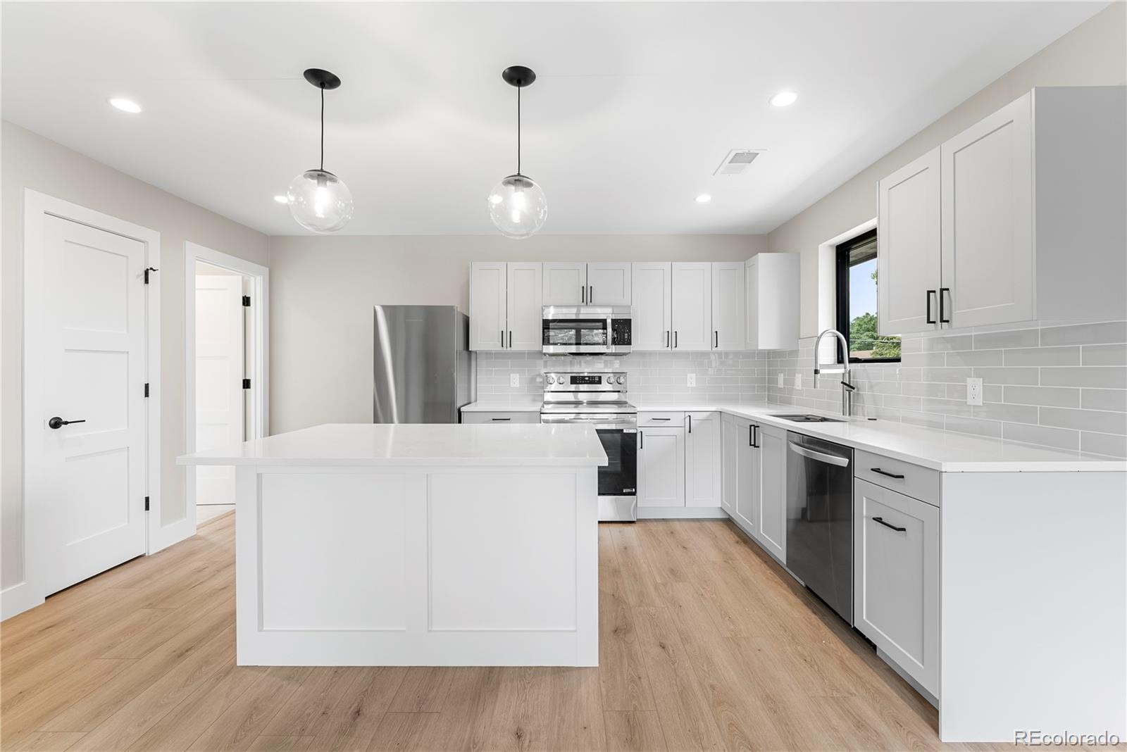 4494 Meade Street Denver, CO 80211 - Photo 32 of 36 a large white kitchen with stainless steel appliances