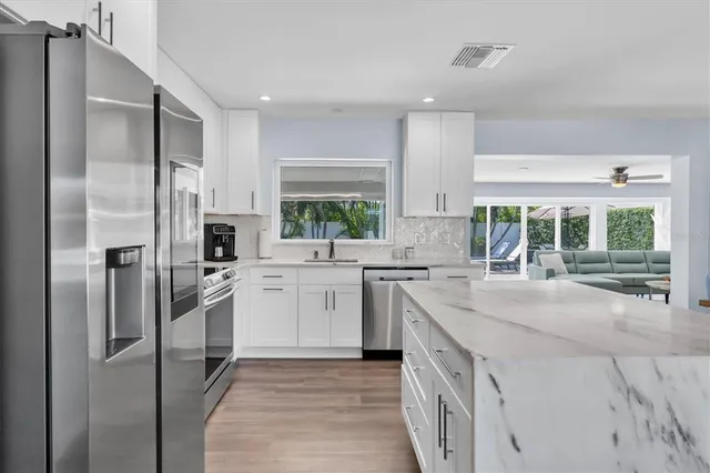 a kitchen with stainless steel appliances granite countertop a stove top oven a sink dishwasher and a refrigerator with wooden floor