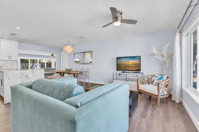 a living room with furniture a dining table wooden floor and a large window