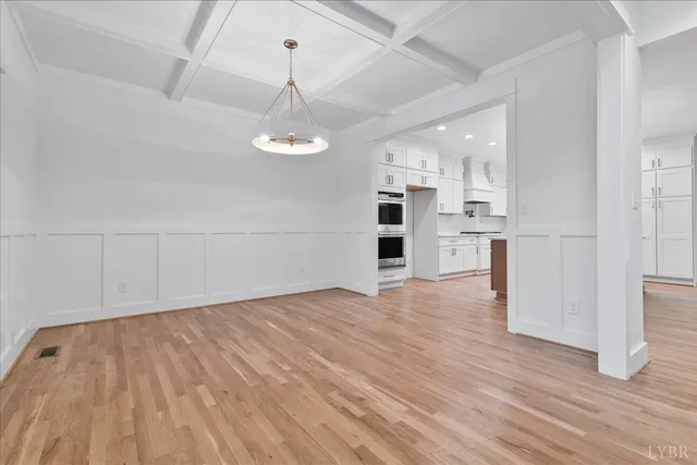 a view of an empty room with wooden floor and a fireplace