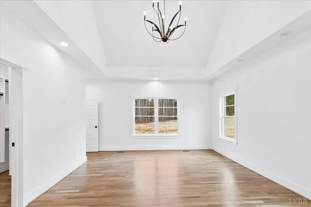 an empty room with wooden floor cabinet and windows