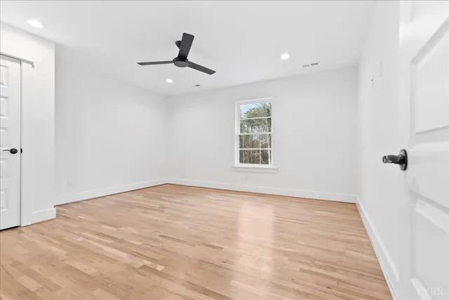 an empty room with wooden floor cabinet and windows
