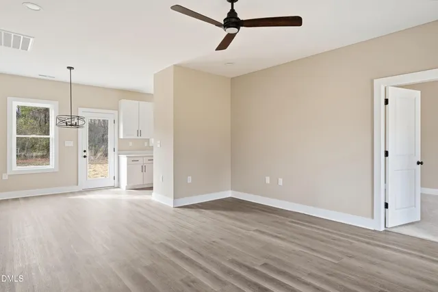 a view of empty room with wooden floor and window