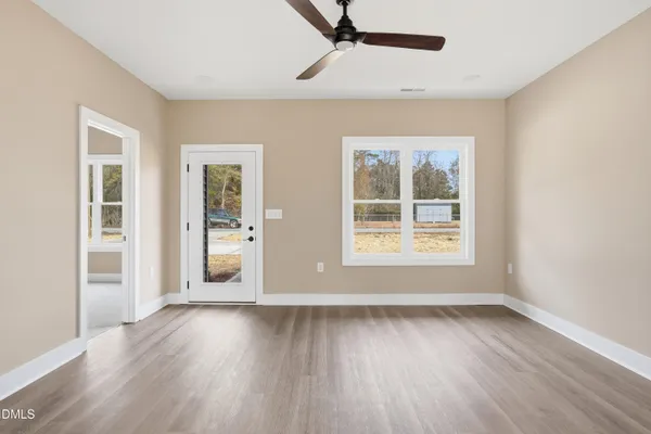 a view of an empty room with wooden floor and a window