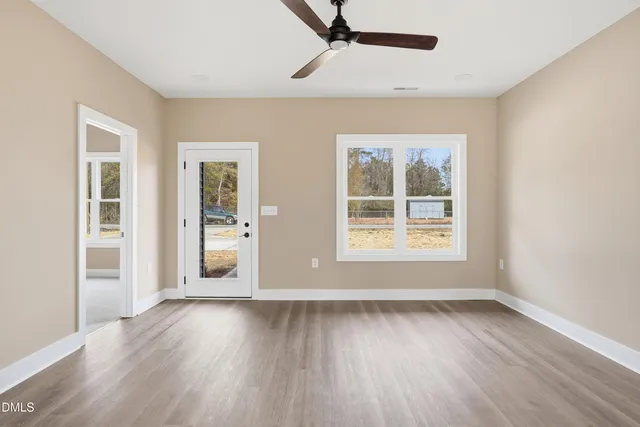 a view of an empty room with wooden floor and a window