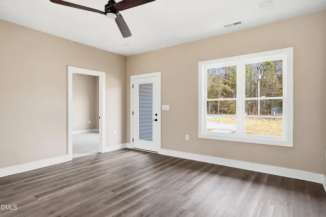an empty room with wooden floor cabinet and windows